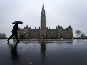 Pedestrians make their way across Parliament Hill in Ottawa. A preliminary estimate of the federal books says the government posted a surplus of $3.1 billion through the first 11 months of the fiscal year.
