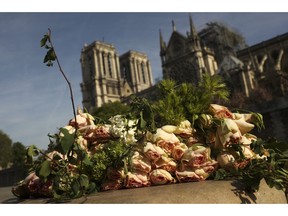 A bunch of flowers lies by the Seine riverside near the Notre Dame cathedral, background, in Paris, Thursday, April 18, 2019. France is paying a daylong tribute Thursday to the Paris firefighters who saved the internationally revered Notre Dame Cathedral from collapse and rescued its treasures from encroaching flames.