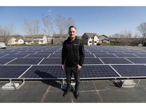 In this April 15, 2019, photo, Todd Miller stands next to solar panels on the roof of his solar installation business in Ankeny, Iowa. For years wind and solar were friendly twins in the campaign for green alternatives to fossil fuels, but the relationship is getting ugly in a number of states, especially in Iowa, where more than 4,000 turbines generate 37 percent of the state's electricity, the second highest rate in the country.