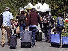 A family heads toward a tent in Saint-Bernard-de-Lacolle, Quebec, stationed by Royal Canadian Mounted Police, as they cross the border at Champlain, N.Y. into Canada.