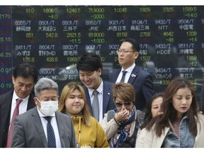 People stand in front of an electronic stock board of a securities firm in Tokyo, Wednesday, April 17, 2019. Shares were mixed in a narrow range Wednesday as China announced its economy grew at a 6.4 percent annual pace in the last quarter.
