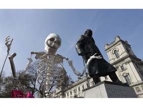 A skeleton is carried past the Winston Churchill statue as demonstrators take part in a 'Funeral Procession' during a climate protest in Parliament Square in London, Monday, April 15, 2019. Extinction Rebellion have organised a nationwide week of action, they are calling for a full-scale Rebellion to demand decisive action from governments on climate change and ecological collapse. They plan to engage in acts of non-violent civil disobedience against governments in capital cities around the world.