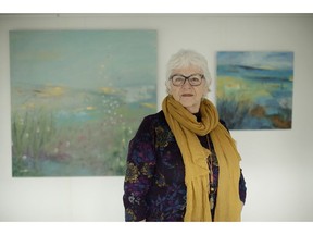 Elly Wright, a Dutch painter who has lived in Britain for 51-years, poses for photographs backdropped by two of her paintings at her home in Epsom, on the south west edge of London, Wednesday, April 10, 2019.  Britain's seemingly endless debate over leaving the European Union has brought division, strife and fear of foreigners, and the trauma has shattered Wright's sense of belonging.
