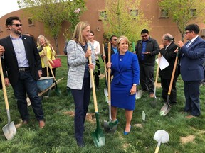 FILE - In this Monday, April 22, 2019 file photo, Gov. Michelle Lujan Grisham, center right, and PNM Resources CEO Pat Vincent-Collawn, center left, celebrate after planting a tree for Earth Day in Albuquerque, N.M. The two leaders gathered with dozens of other state, tribal and local officials to announce that PNM, New Mexico's largest electric provider, was setting a goal to be emissions-free by 2040.