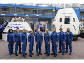 FILE - This undated photo made available by NASA on Aug. 3, 2018 shows mockups of Boeing's CST-100 Starliner and SpaceX's Crew Dragon capsules with crew members, from left, Sunita Williams, Josh Cassada, Eric Boe, Nicole Mann, Christopher Ferguson, Douglas Hurley, Robert Behnken, Michael Hopkins and Victor Glover at the Johnson Space Center in Texas. Boe, pulled for unspecified medical reasons in January 2019, was replaced by Mike Fincke. The Starliner capsule, supposed to make its debut in April 2019, was pushed back until August. SpaceX's Dragon capsule could fly with a test crew in the summer of 2019, but the schedule is under review. (NASA via AP)