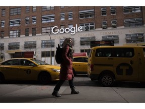 FILE- In this Dec. 17, 2018, file photo a woman walks past Google offices in New York. Alphabet Inc., parent company of Google, reports financial results on Monday, April 29, 2019.