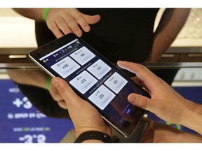 In this March 19, 2019, photo Zack Shelton, of Swish Analytics, left, explains how to place a bet at the Skyloft Predictive Gaming Lounge inside the Golden 1 Center, home of the NBA's Sacramento Kings, in Sacramento, Calif. Although sports betting is not legal in California, the SkyLoft Lounge is being used for contests that don't involve gambling.