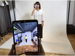 FILE - In this April 16, 2019, file photo, a model holds a Samsung Galaxy Fold smart phone to her face, during a media preview event in London. Samsung is pushing back this week's planned public launch of its highly anticipated folding phone after reports that reviewers' phones were breaking. The company had been planning to release the Galaxy Fold on Friday. Instead, it says it will to run more tests and announce a new launch date in the coming weeks.