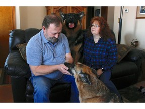 In this Feb. 21, 2019, photo, Joe and Deb Colgan sit with their German shepherds Gracie, on the floor, and Takaani, on the couch, in their home in Oconomowoc, Wis. The Colgans started feeding their two previous dogs raw meat seven years ago and continued with Gracie and Takaani because they say they have less health problems and cleaner teeth. U.S. pet owners are increasingly feeding raw, freeze dried or lightly cooked meat and vegetables to their dogs and cats.