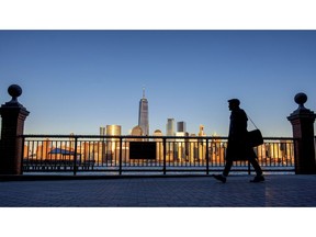 FILE - In this March 26, 2019 file photo, an evening commuter is silhouetted against the glistening New York City skyline at sunset as he walks along Hudson River shoreline in Jersey City, N.J. On Wednesday, April 17, the Federal Reserve releases its latest "Beige Book" survey of economic conditions.