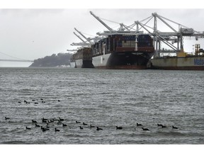 FILE - In this March 6, 2019, file photo, container ships docked at the Port of Oakland wait to be unloaded in Oakland, Calif. On Wednesday, April 17, the Commerce Department reports on the U.S. trade gap for February.