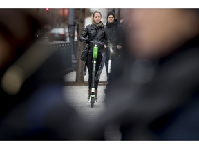 In this Dec. 4, 2018, photo a couple rides scooters near the White House in Washington. Electric scooters are overtaking station-based bicycles as the most popular form of shared transportation outside transit and cars.