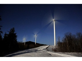 The blades of wind turbines spin under the light of a full moon at the Saddleback Ridge Wind Project in Carthage, Maine.