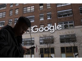 FILE - In this Dec. 17, 2018, file photo, a man using a mobile phone walks past Google offices in New York. Executives from Google and Facebook are facing Congress Tuesday, April 8, 2019, to answer questions about their role in the hate crimes and the rise of white nationalism in the U.S.