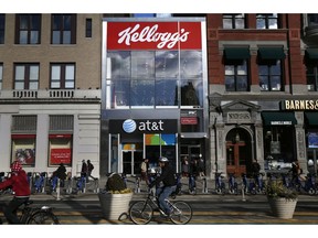 FILE- In this Dec. 14, 2017, file photo people bike and walk by Kellogg's NYC Cafe at Union Square in New York. Kellogg is selling its iconic Keebler cookie brand and other sweet snacks businesses to Ferrero for $1.3 billion.