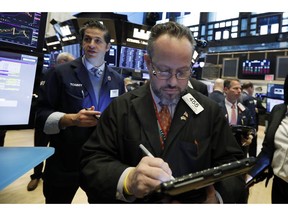 FILE- In this March 7, 2019, file photo Robert Arciero, center, works with fellow traders on the floor of the New York Stock Exchange. The U.S. stock market opens at 9:30 a.m. EDT on Thursday, April 4.
