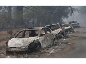 FILE - This Nov. 9, 2018, file photo the burned out hulks of cars abandoned by their drivers sit along a road in Paradise, Calif. The scale of disaster in the Camp Fire was unprecedented, but the scene of people fleeing wildfire was familiar, repeated numerous times over the past three years up and down California from Redding and Paradise to Santa Rosa, Ventura and Malibu.