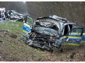 A damaged police car is seen next to a road in Langen near Frankfurt, Germany, Sunday, March 31, 2019. The police car with two police officers was on the way to a nearby plane crash as it collided with another car, background, carrying two young people who died in the crash. The police officers were seriously injured.