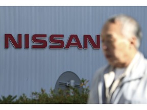In this Jan. 9, 2019, photo, a man walks past the logo at global headquarters of Nissan Motor Co., Ltd. in Yokohama, near Tokyo. Nissan has lowered its profit forecast for the fiscal year through March as the Japanese automaker, contends with slowing sales and the fallout from the loss of its former chairman, Carlos Ghosn. Nissan Motor Co. said Wednesday, April 24, 2019 it expects to post a 319 billion yen profit ($2.9 billion) for the fiscal year, marking a 22 percent drop from its earlier 410 billion yen ($3.7 billion) profit forecast earlier.