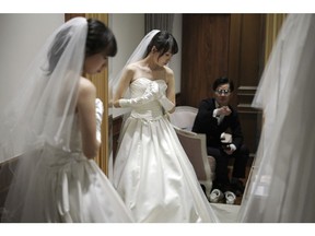 In this April 11, 2019, photo, Kenzo Watanabe, right, looks at his fiancee Chiharu Yanagihara trying on a wedding dress at a Japanese wedding company in Tokyo. Japan is getting ready for its biggest celebration in years with the advent of the Reiwa era of soon-to-be emperor Naruhito. That means big opportunities for businesses hoping consumers will splash out on long holidays and memorabilia.