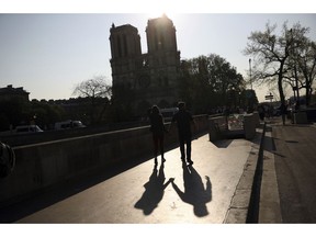 Two people walk by a the Notre Dame Cathedral in Paris, Saturday, April 20, 2019. Yellow vest protests are scheduled to take place in Paris and other regions of France over the weekend, with a heightened security presence anticipated.