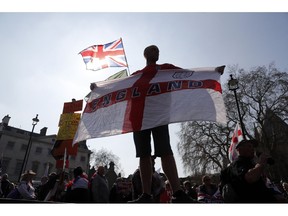 A Brexit supporter holds an England flag at Parliament Square in Westminster, London, Friday, March 29, 2019. Pro-Brexit demonstrators were gathering in central London on the day that Britain was originally scheduled to leave the European Union. British lawmakers will vote Friday on what Prime Minister Theresa May's government described as the "last chance to vote for Brexit."