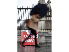 A pro Brexit placard placed on the ground as a pedestrian walks past the Houses of Parliament in London, Wednesday, April 3, 2019. With Britain racing toward a chaotic exit from the European Union within days, Theresa May veered away from the cliff-edge Tuesday, saying she would seek another Brexit delay and hold talks with the opposition to seek a compromise.