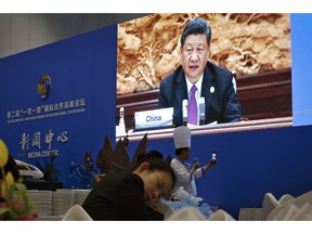 A chef takes a selfie near a live broadcast image of Chinese President Xi Jinping speaking at the leaders summit of the Belt and Road Forum, at the media center in Beijing, Saturday, April 27, 2019.