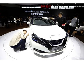 FILE - In this April 25, 2018, file photo, a visitor takes a closer look at the Sylphy Zero Emission during the start of the Auto China 2018 in Beijing, China. The 2019 Shanghai auto show highlights the global industry's race to transform electric cars into a profitable product Chinese drivers want to buy as Beijing winds down multibillion-dollar subsidies that made this country the biggest market for the technology.