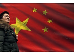 In this photo taken Friday, March 1, 2019, a woman walks by Chinese flag placed on a street in Belgrade, Serbia. Chinese investments have been booming throughout Central and Eastern Europe's cash-strapped developing countries, even as European Union officials scramble to counter Beijing's mounting economic and political influence the EU has branded a ''systematic rival.''