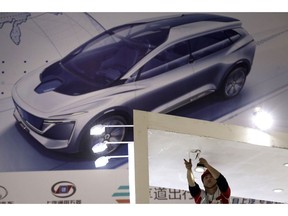 A worker installs lightings before the start of the Auto Shanghai 2019 show in Shanghai on Monday, April 15, 2019. This year's Shanghai auto show which starts Thursday highlights the global industry's race to make electric cars Chinese drivers want to buy as Beijing winds down subsidies that promoted sales.