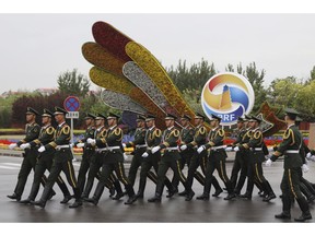 Chinese paramilitary policemen march past a decor for the Belt and Road Forum outside the special plane terminal of the Beijing International airport where foreign leaders are expected to arrive in Beijing on Wednesday, April 24, 2019.