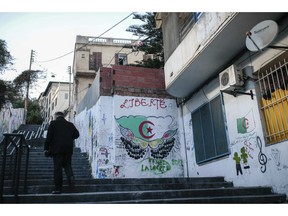 A man walks past street art that reads "liberty," supporting the current protest that has forced out longtime President Abdelaziz Bouteflika, in downtown Algiers, Algeria, Monday, April 8, 2019. The pro-democracy movement has forced out Bouteflika and demanded that other top figures leave too.