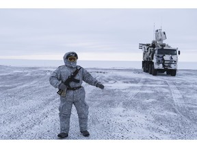 In this photo taken on Wednesday, April 3, 2019, a Russian solder stands guard as Pansyr-S1 air defense system, right, is parked on Kotelny Island, part of the New Siberian Islands archipelago located between the Laptev Sea and the East Siberian Sea, Russia.  Missile launchers ply icy roads and air defense systems point menacingly into the sky at this Arctic military outpost _ a key vantage point for Russia to project power to the resource-rich polar region. Russia, has made reaffirming its presence in the Arctic the top goal. The region is believed to hold up to one-quarter of the planet's undiscovered oil and gas.