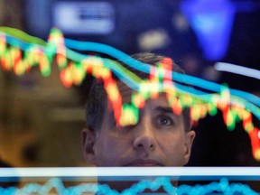 Specialist Anthony Rinaldi is reflected in a screen at his post on the floor of the New York Stock Exchange.