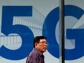 A man walks by a 5G network advertisement on display at a shopping district in Beijing, Wednesday, May 15, 2019.