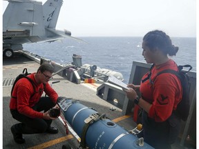 In this Wednesday, May 15, 2019, photo released by the U.S. Navy, Aviation Ordnanceman 3rd Class Alexandrina Ross, right, and Aviation Ordnanceman Airman Hunter Musil, left, inspect a bomb on the USS Abraham Lincoln while it sails in the Arabian Sea. U.S. diplomats warned Saturday, May 18, 2019, that commercial airliners flying over the wider Persian Gulf faced a risk of being "misidentified" amid heightened tensions between the U.S. and Iran.