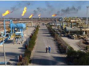 FILE - in this Thursday, Jan. 12, 2017 file photo, laborers walk in the Nihran Bin Omar field north near Basra, Iraq. Prime Minister Adel Abdul-Mahdi said Tuesday, May 7, 2019 that he has instructed Iraq's Oil Ministry to finalize an agreement with global energy giants ExxonMobil and PetroChina to lead a $53 billion megaproject to boost oil production.