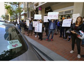 Uber and Lyft drivers carry signs during a demonstration outside of Uber headquarters Wednesday, May 8, 2019, in San Francisco. As Uber executives lure investors to infuse the company with billions of dollars ahead of the largest technology IPO this year, the men and women behind the wheels of the largest ride-hailing companies are pushing for higher wages and recognition for their role in building the companies.