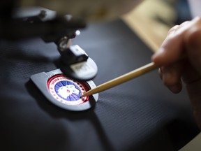 An employee arranges a logo patch in a sewing machine at the new Canada Goose Inc. manufacturing facility in Montreal