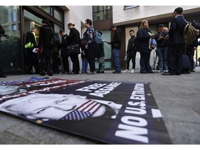 A poster lays on the pavement as supporters and journalists queue at the entrance of Westminster Magistrates Court in London, Thursday, May 2, 2019, where WikiLeaks founder Julian Assange is expected to appear by video link from prison.  Assange is facing a court hearing over a U.S. request to extradite him for alleged computer hacking.