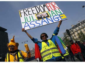 A man wearing a yellow vest holds a banner reading "Freedom for Julian Assange", during a May Day demonstration in Paris, Wednesday, May 1, 2019. French authorities announced tight security measures for May Day demonstrations, with the interior minister saying there was a risk that "radical activists" could join anti-government yellow vest protesters and union workers in the streets of Paris and across the country.