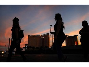 FILE - In this April 1, 2018, file photo, people carry flowers as they walk near the Mandalay Bay hotel and casino during a vigil for victims and survivors of a mass shooting in Las Vegas. Casino giant MGM Resorts is telling federal regulators it thinks it might pay up to $800 million to settle liability lawsuits stemming from the October 2017 mass shooting that became the deadliest in modern U.S. history.