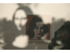 In this photo taken Wednesday, May 15, 2019, in a display of female icons, Elizabeth Taylor is reflected in an image of the Mona Lisa at the exhibition, "Andy Warhol _ From A to B and Back Again" in San Francisco. A retrospective of Andy Warhol's work on display at the San Francisco Museum of Modern Art captures his use of artwork to give his subjects personas the way people do now using social media.