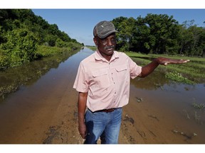 In this Thursday, May 23, 2019 photo, Larry Walls, a farmer and businessman stands at the edge of a backwater flooded road leading to his 560 acres of rented farm land near Louise, Miss. Walls can no longer drive to the property without the possibility of getting flooded or stuck. Four months into what seems like a never-ending flood, he's been trying to stay busy. He pressure-washed his church, and he's been shooting the snakes that slither out of a swollen creek submerging his backyard.