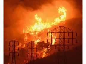 FILE - This Dec. 16, 2017 file photo provided by the Santa Barbara County Fire Department shows flames burning near power lines in Montecito, Calif. A California commission set up to study wildfire issues is strongly recommending that the state change a liability standard imperiling major utilities in a report released Wednesday, May 29, 2019. But Democratic leaders say they won't tackle the hot-button topic for now.