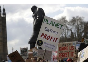 FILE - In this Friday, April 12, 2019 file photo, climate change demonstrators hold banners in front of the Winston Churchill Statue during a protest near Parliament in London. An independent committee that advises the British government on climate change says the UK should target net-zero emissions of greenhouse gases by 2050, recommending the rapid adoption of policies to change everything from how people heat their homes to what they eat. The report released Thursday, May 2 by the Committee on Climate Change stresses that it is time for ambitious goals to curb the emissions that cause climate change.