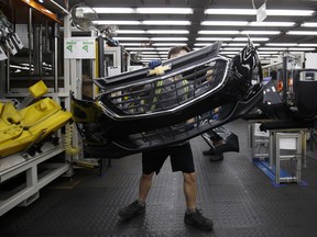 n employee carries a General Motors Co. (GM) Chevrolet bumper at the Magna International Inc. Polycon Industries auto parts manufacturing facility in Guelph, Ontario.