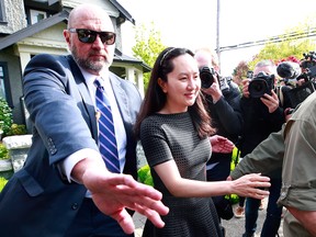 Technologies Chief Financial Officer Meng Wanzhou is escorted by security as she leaves her home on May 8, 2019 in Vancouver.