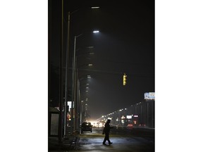In the Thursday, May 2, 2019 photo, a pedestrian crosses Gratiot Street at Outer Drive East under a bright streetlight flanked by dimmer streetlights in Detroit.  The city's Public Lighting Authority said a manufacturer is to blame for the premature failure of about one third the LED streetlights installed as the city embarked on municipal bankruptcy.